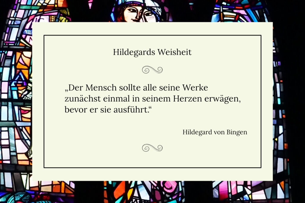 Hellcremefarbene Karte mit dem Hildegard-von-Bingen-Zitat „Der Mensch sollte alle seine Werke zunächst einmal in seinem Herzen erwägen, bevor er sie ausführt" vor buntem Kirchen-Bleiglasfenster.