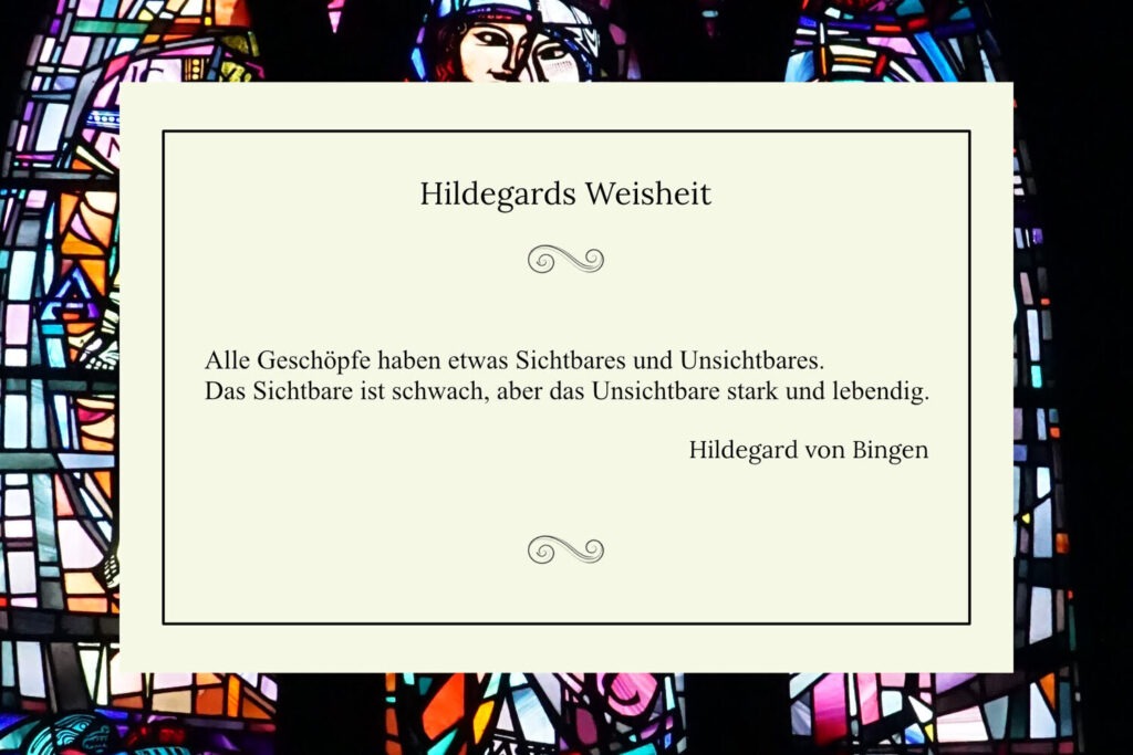 Zitatkarte mit dem Spruch „Alle Geschöpfe haben etwas Sichtbares und Unsichtbares“ von Hildegard von Bingen vor einem farbenfrohen Glasfenster.